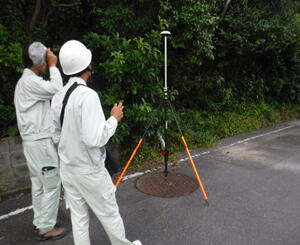 道路沿いで測量する作業員